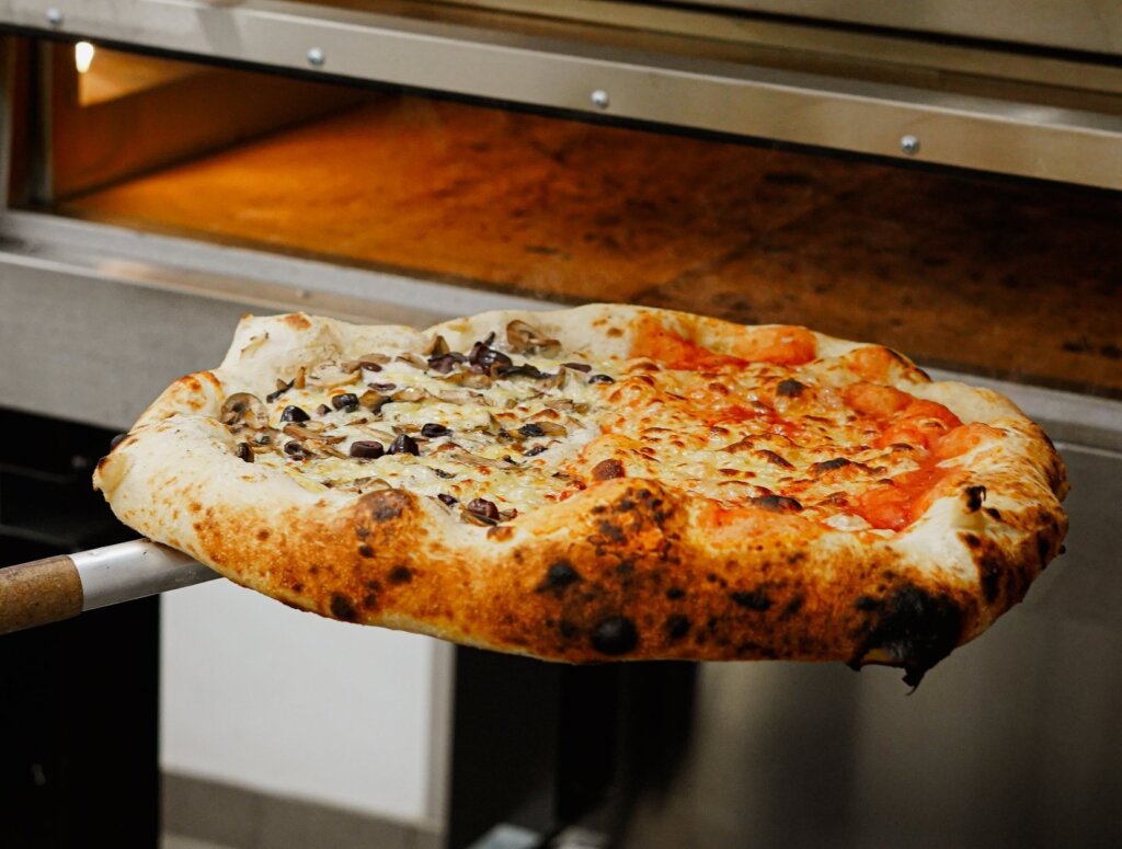 A Pizza being removed from the oven at Tony's Pizza